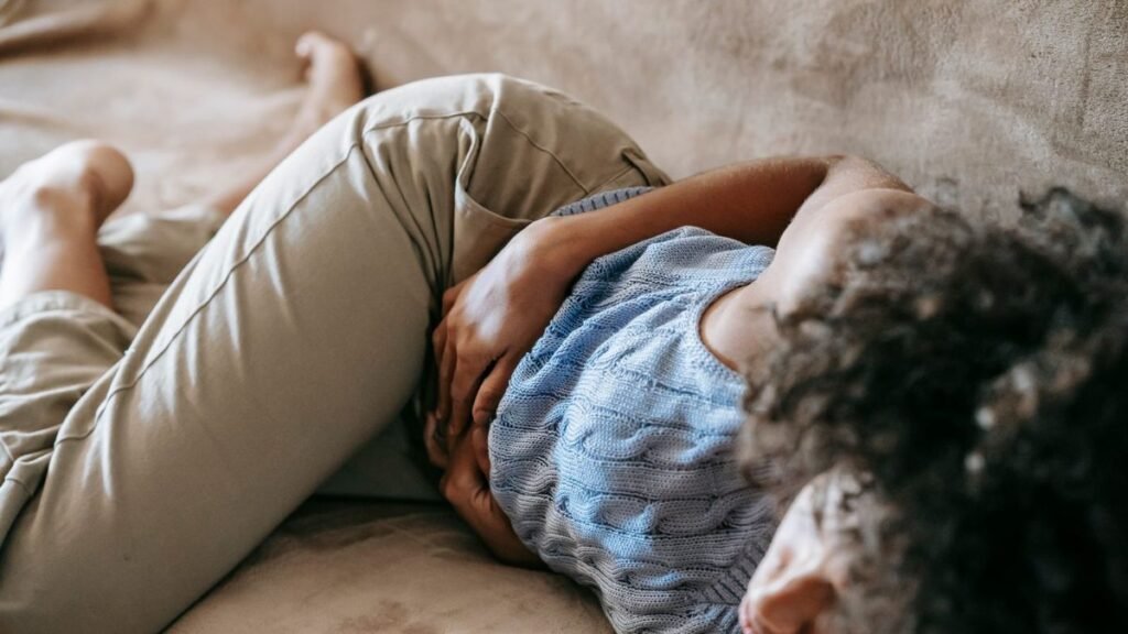 Woman lying on a sofa holding her left side in pain